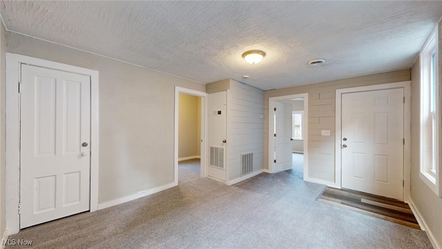 carpeted entryway with a textured ceiling