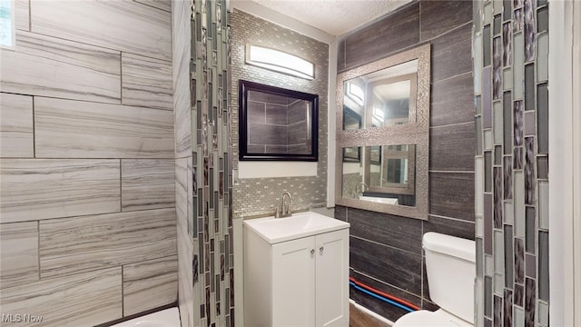 bathroom with tasteful backsplash, a tile shower, vanity, tile walls, and toilet