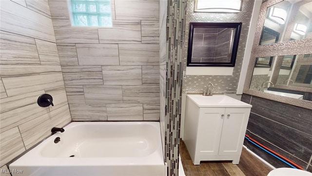 bathroom with vanity, tiled shower / bath, and tasteful backsplash