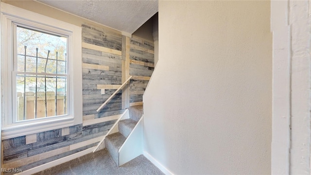 stairway with carpet floors and a textured ceiling