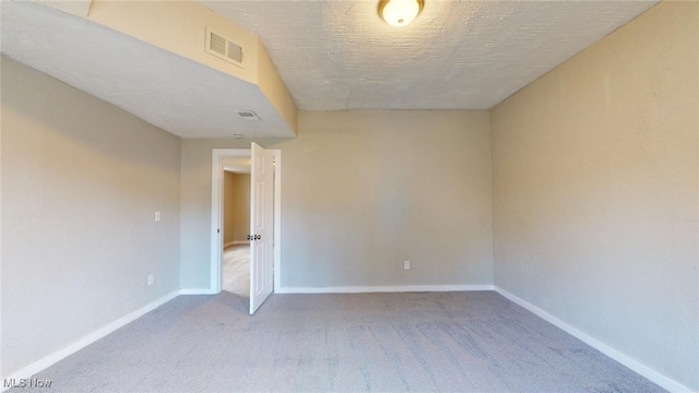 spare room featuring carpet and a textured ceiling