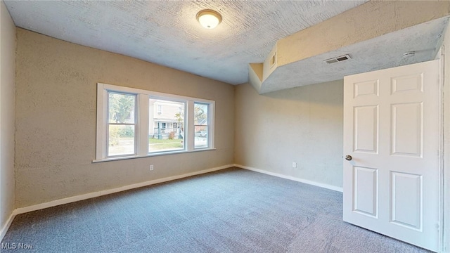 carpeted spare room featuring a textured ceiling