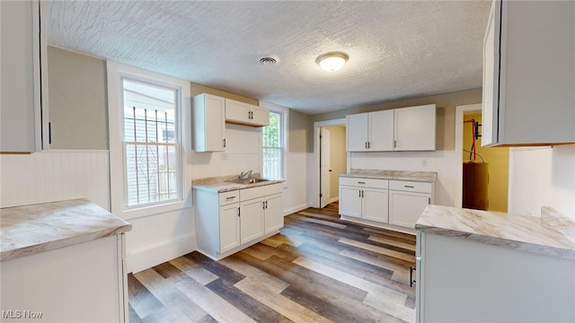 kitchen with white cabinetry, sink, a textured ceiling, and light wood-type flooring