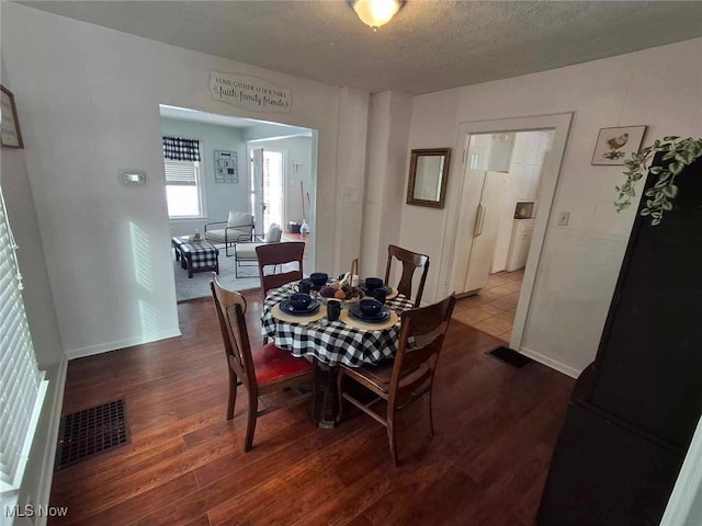 dining space with dark wood-type flooring and a textured ceiling