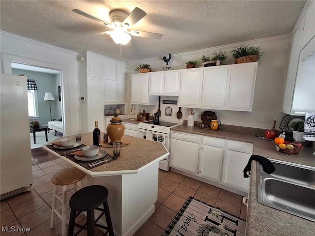 kitchen featuring light tile patterned flooring, white cabinetry, white electric stove, and freestanding refrigerator