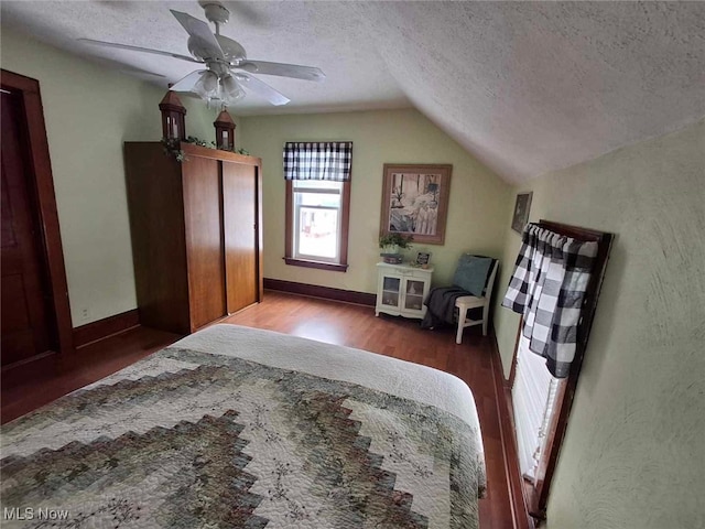 bedroom with wood finished floors, a ceiling fan, a textured ceiling, and lofted ceiling