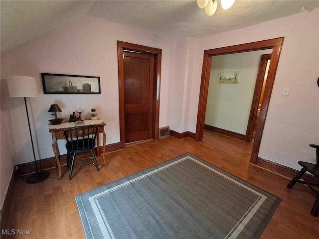 hall with hardwood / wood-style flooring and lofted ceiling