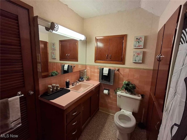 bathroom featuring vanity, toilet, a textured ceiling, and tile walls