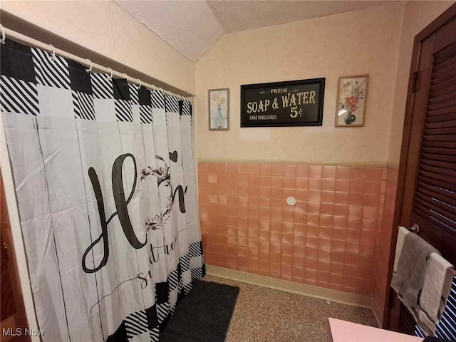 bathroom with tile walls, curtained shower, and vaulted ceiling