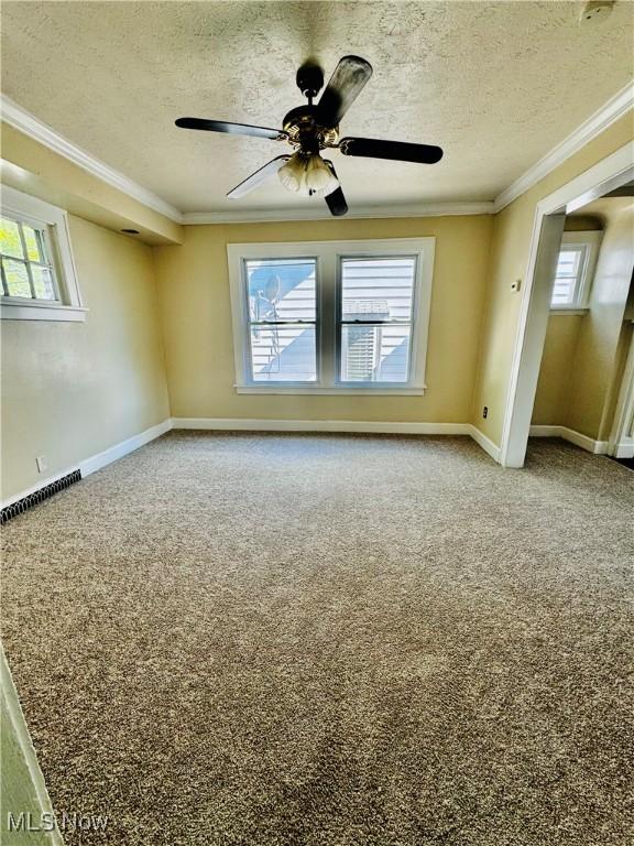 empty room featuring ceiling fan, a textured ceiling, and ornamental molding