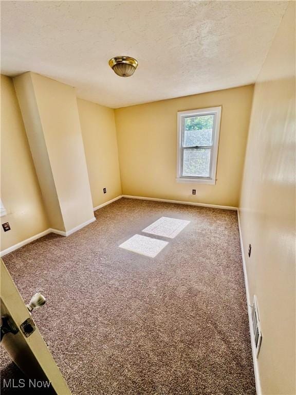 empty room featuring a textured ceiling and carpet