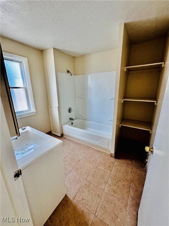 bathroom featuring vanity, tub / shower combination, and a textured ceiling