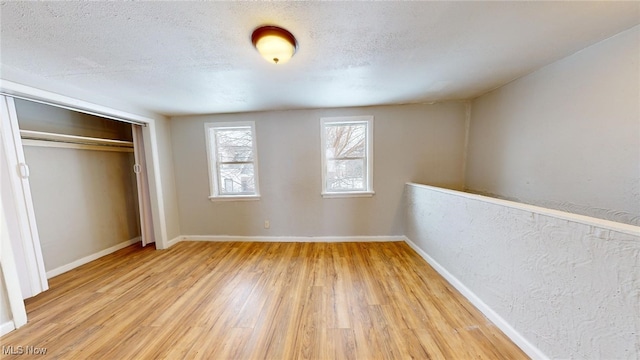 unfurnished bedroom with a closet, a textured ceiling, and light wood-type flooring