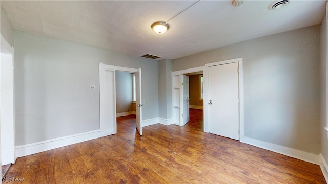 spare room with a textured ceiling and hardwood / wood-style flooring