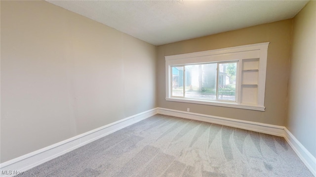 spare room with light carpet and a textured ceiling