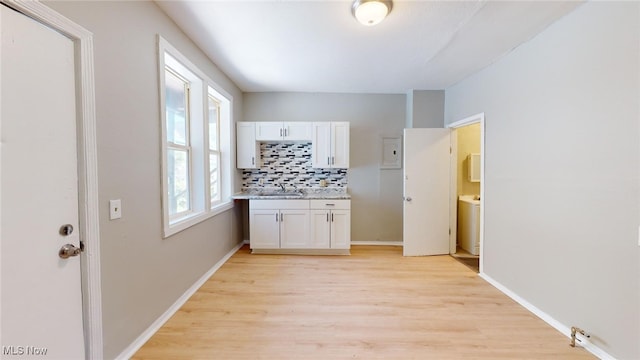 kitchen featuring decorative backsplash, white cabinetry, light hardwood / wood-style flooring, and sink