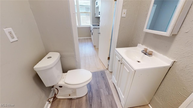 bathroom with hardwood / wood-style floors, vanity, and toilet