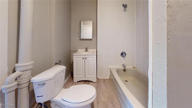 bathroom with hardwood / wood-style floors, vanity, a bath, and toilet