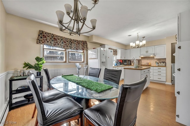 dining area with a chandelier, light hardwood / wood-style flooring, and a baseboard heating unit