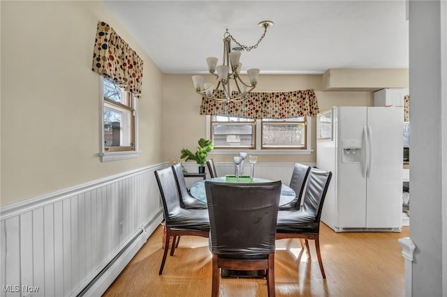 dining area with a chandelier, light hardwood / wood-style floors, a wealth of natural light, and a baseboard heating unit