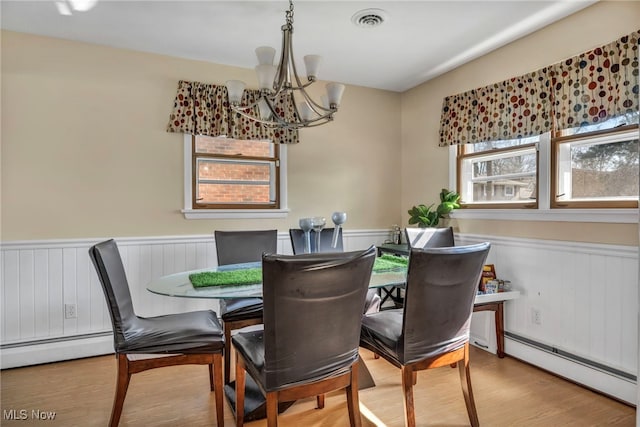 dining area with a chandelier, hardwood / wood-style flooring, and baseboard heating