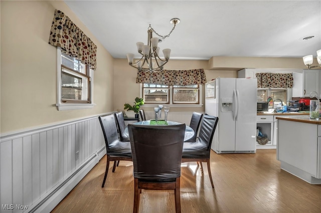 dining space featuring baseboard heating, plenty of natural light, a chandelier, and light hardwood / wood-style floors