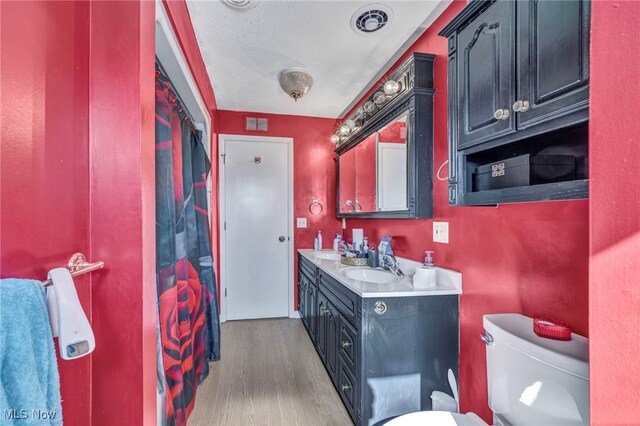 bathroom with hardwood / wood-style floors, vanity, toilet, and a shower with curtain