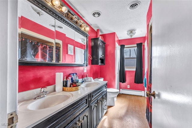 bathroom with vanity, toilet, a textured ceiling, baseboard heating, and wood-type flooring