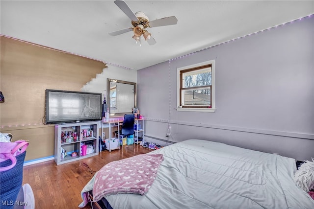 bedroom with baseboard heating, ceiling fan, and hardwood / wood-style floors