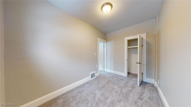 unfurnished bedroom with light carpet and a closet