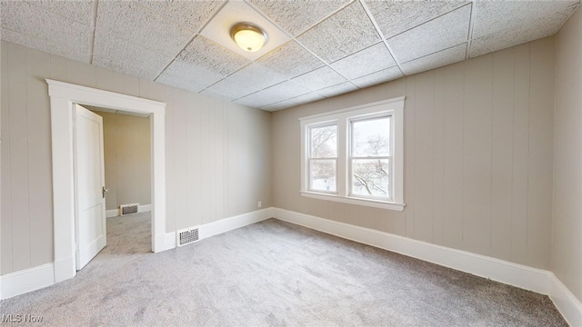 empty room featuring a drop ceiling and light colored carpet