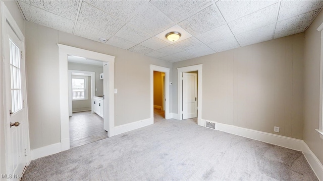 carpeted empty room with a paneled ceiling