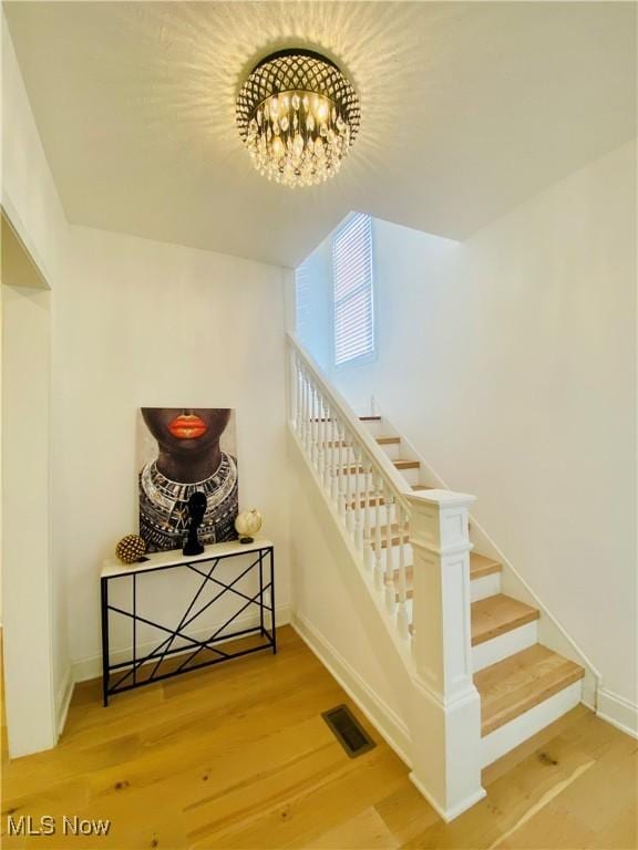 stairway featuring wood-type flooring and a notable chandelier