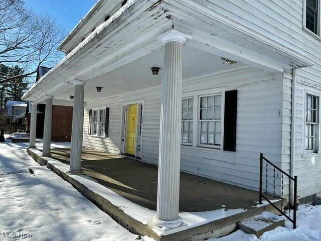 snow covered property featuring covered porch