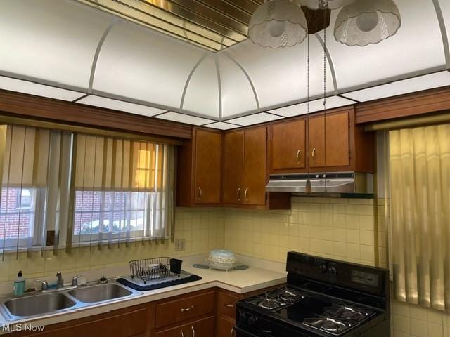 kitchen with tasteful backsplash, plenty of natural light, black range, and sink