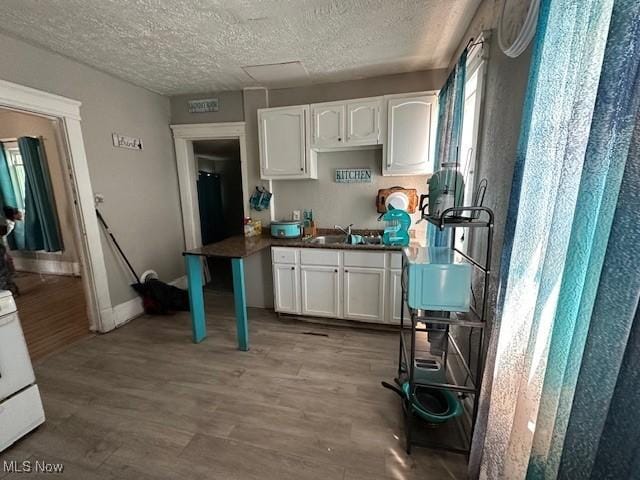 kitchen featuring a textured ceiling, sink, light hardwood / wood-style flooring, white cabinets, and white stove