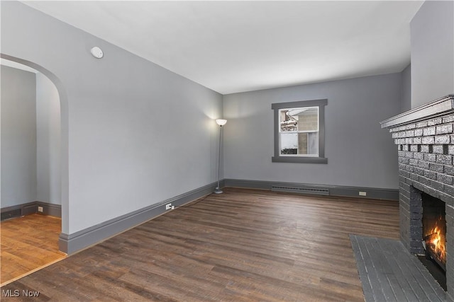 unfurnished living room featuring dark hardwood / wood-style floors and a brick fireplace