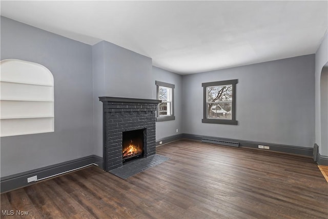 unfurnished living room featuring built in shelves, a fireplace, and dark hardwood / wood-style flooring