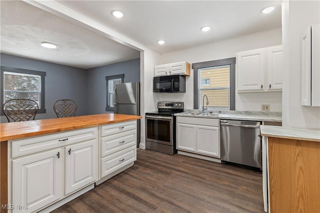 kitchen with butcher block countertops, dark hardwood / wood-style floors, white cabinetry, and stainless steel appliances