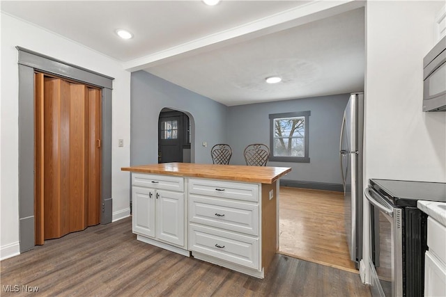 kitchen featuring dark hardwood / wood-style flooring, white cabinets, stainless steel appliances, and wood counters