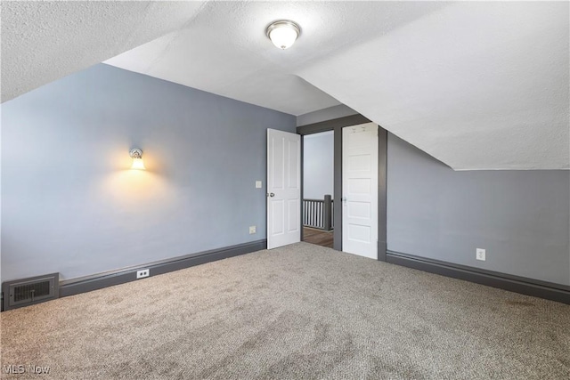 additional living space with carpet flooring, a textured ceiling, and vaulted ceiling