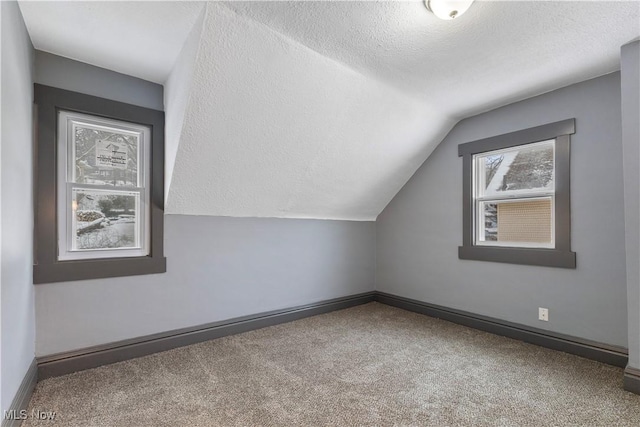 bonus room featuring a textured ceiling, carpet flooring, and vaulted ceiling