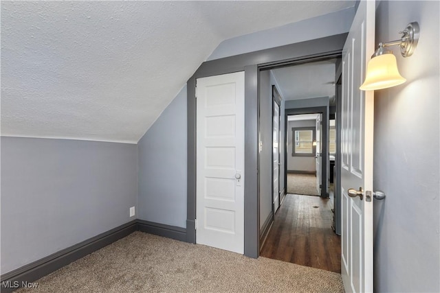 bonus room with a textured ceiling, dark carpet, and lofted ceiling