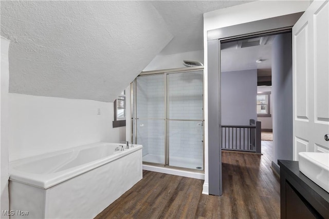 bathroom with vanity, vaulted ceiling, hardwood / wood-style flooring, a textured ceiling, and independent shower and bath