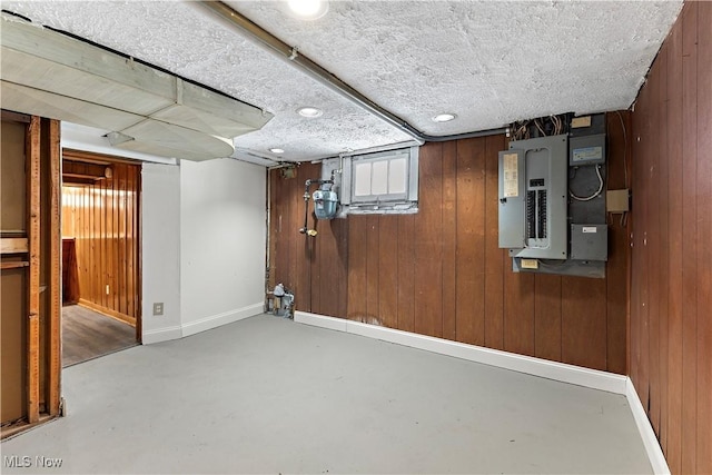 basement featuring electric panel and wood walls