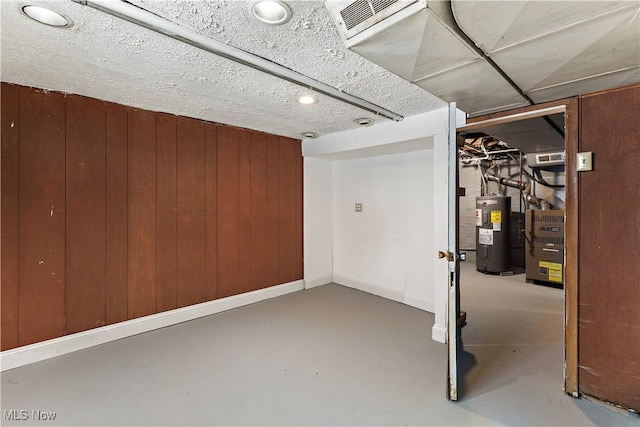 basement featuring wood walls and electric water heater