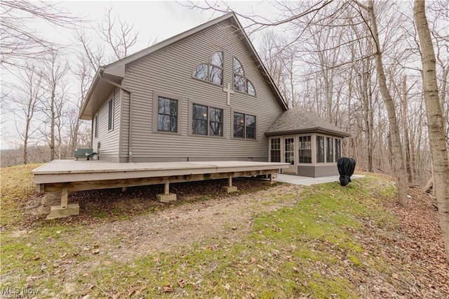 back of property featuring a lawn, a sunroom, and a deck