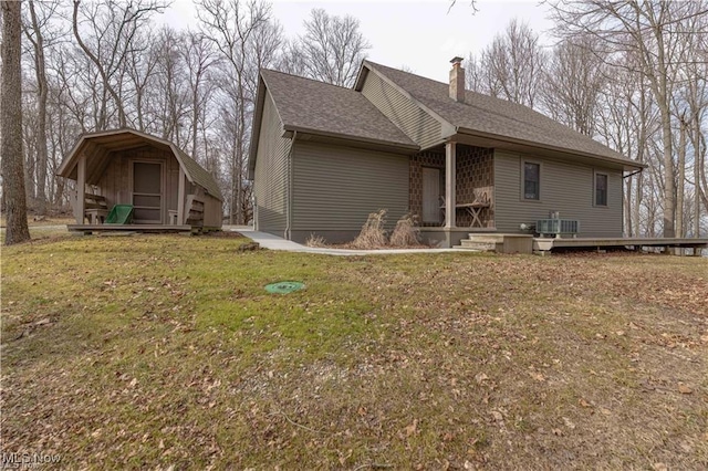 rear view of property with a lawn, central AC, and a storage unit