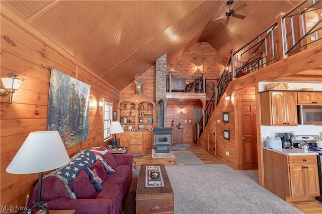 living room featuring built in shelves, vaulted ceiling, ceiling fan, wooden ceiling, and a wood stove