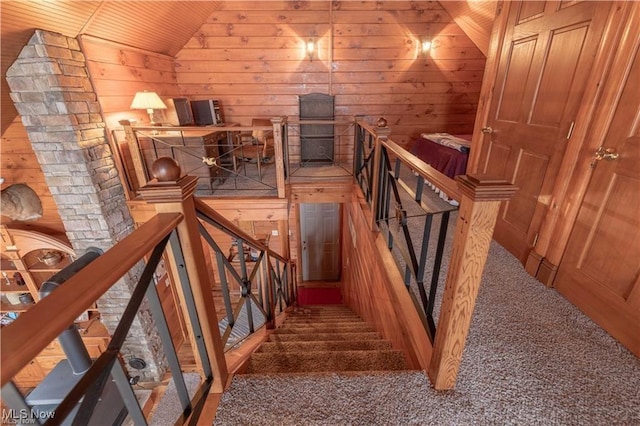 staircase with wood walls, carpet floors, wooden ceiling, and lofted ceiling